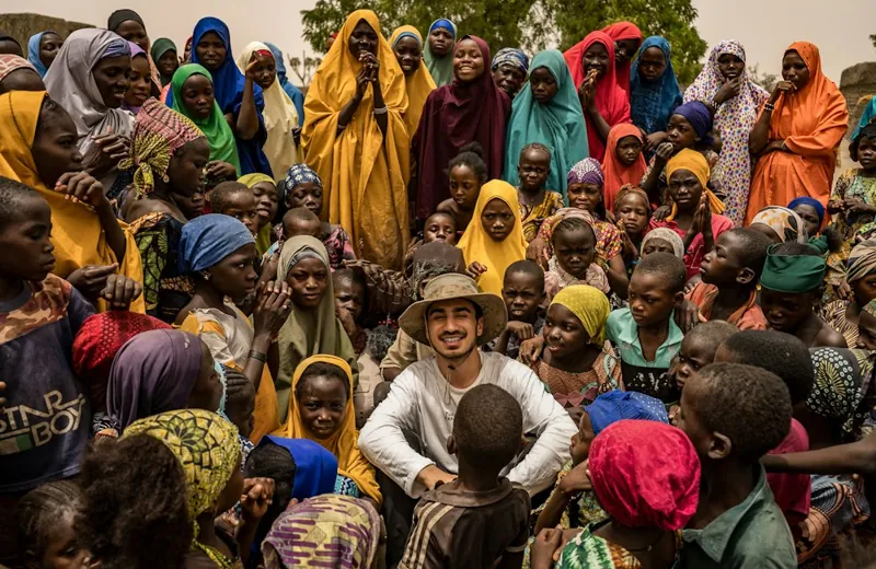 A man surrounded by women and children at a community gathering